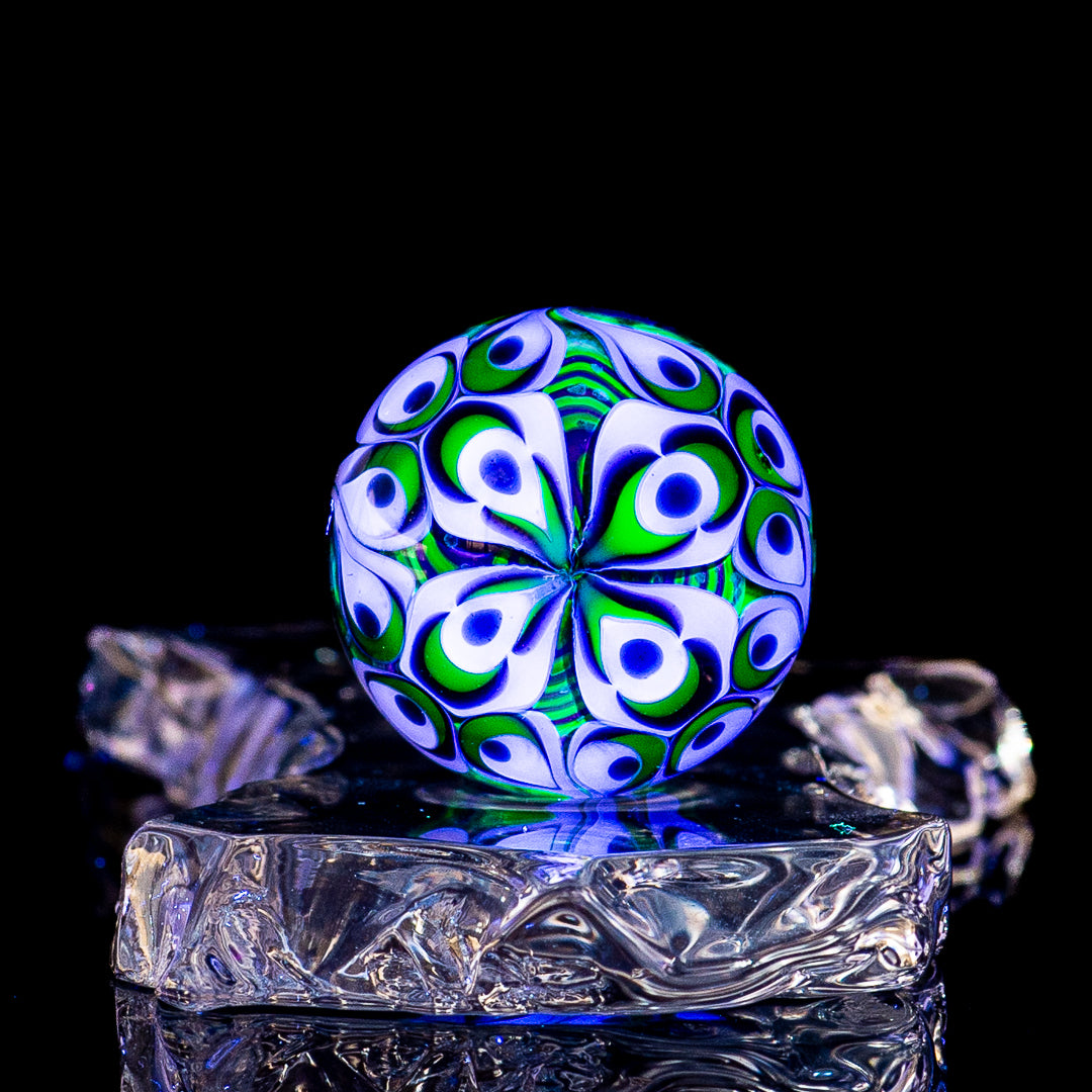 Black Magic UV Pinwheel Top marble by Indo Glass, colorful glass marble with vibrant pinwheel design on a smooth surface.
